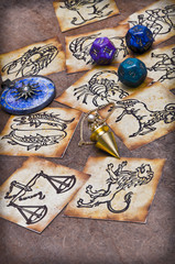 zodiac ring, pendulum, dice with astrology symbols lying on horoscope