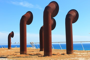 Urban landscape - big industrial pipes against blue sky and sea