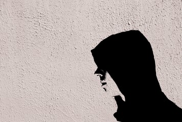 Fototapeta premium Young teenage bully boy in black hoodie with graffiti stencil effect on white concrete textured wall