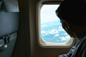 Fototapeta premium Middle-aged man looking out of airplane's window viewing Thailand's landscape below