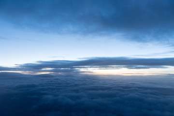 Fototapeta na wymiar Sunrise above clouds seen through airplane window