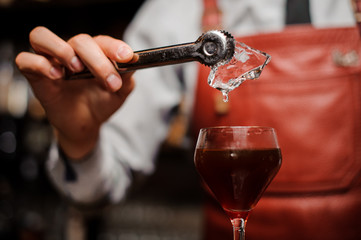 Bartender is putting an ice into the coctail