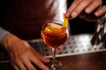 Bartender is decorating a cocktail with lemon zest