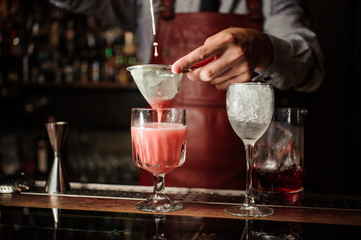 Barman is making alcoholic cocktail at the bar