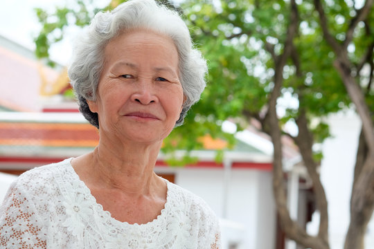 Older Asian women with grayish hair have smiling faces.