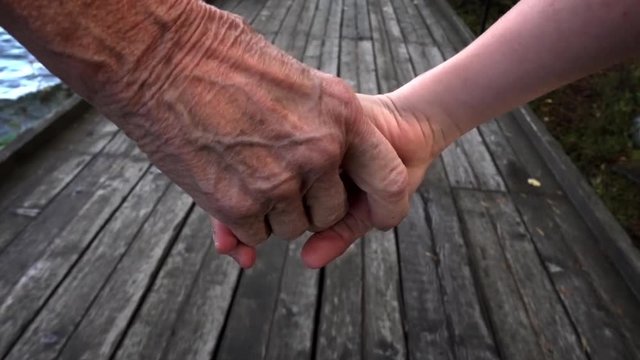 An 8 year old kid and a grandmother holding hands and walking in slow motion