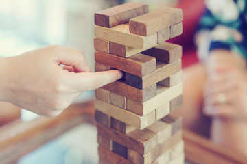 Hand of woman playing a block wood game. Tower stack from wooden blocks toy.