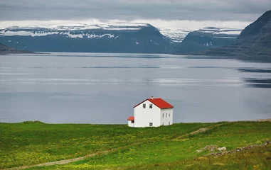Reise nach Island. Das charmante rustikale Landhaus auf dunklem, bewölktem Himmel und Fjordhintergrund © vitaliymateha
