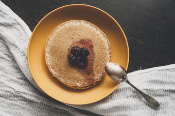 Homemade pancakes on the yellow plate with cherry jam