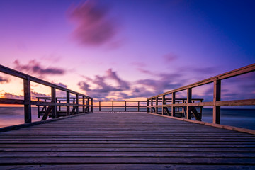 Houten pier op het zeestrand bij zonsondergang
