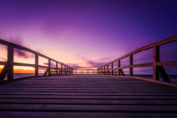 Wooden pier on the sea beach at sunset