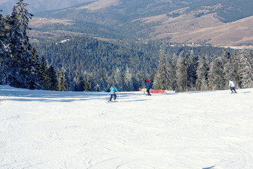 Skier riding on fresh snow go down the ski resort in the mountains at sunny day.