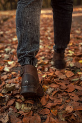 Men's shoes in autumn leaves. A man walking in a park full of autumn leaves