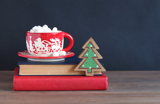 The Christmas red mug on a pile of books on a dark background