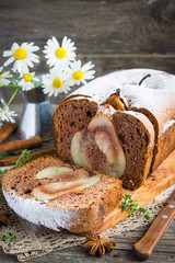 Vanilla cake with pears, cinnamon, thyme on a wooden table.
