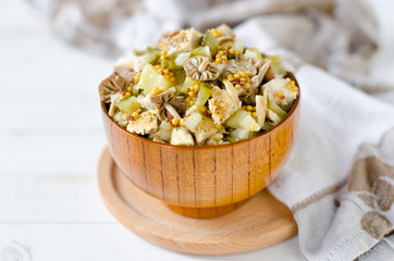 Salad of chicken, potatoes, pickled mushrooms and pickles with parchment from Dijon mustard