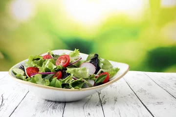 Fotobehang bowl of salad with vegetables and greens, with tomato, cucumber and onions © beats_