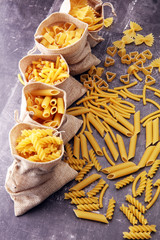 Various mix of pasta on grey rustic background. Diet and food concept