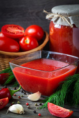Fresh  tomato sauce and red tomatoes with dill, garlic, pepper on a wooden table. Tomatoes conservation.
