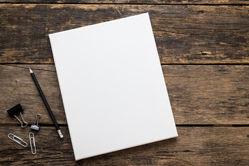 Empty white canvas frame with pencil on a wooden background.
