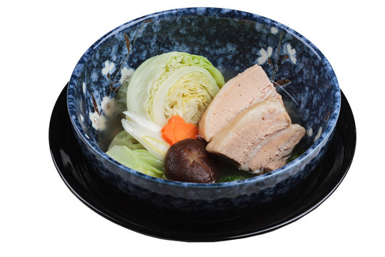 Isolated Pressure cooker pork belly (Kakuni) with cabbage, Japanese scallion, shiitake, carrot served in blue ceramic bowl. 