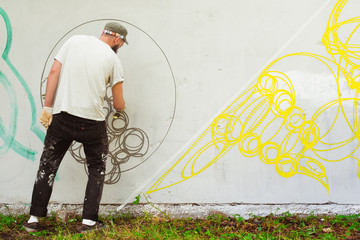 Artists draw graffiti on a fence.