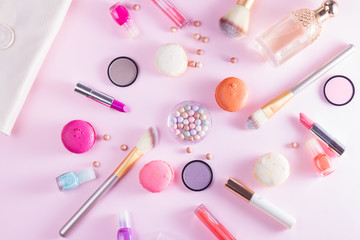 Make up products and macaroons on pink background