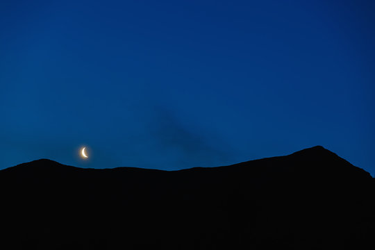 Moon in night sky over mountain ridge