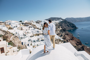 The couple is standing on the roof in Santorini - obrazy, fototapety, plakaty
