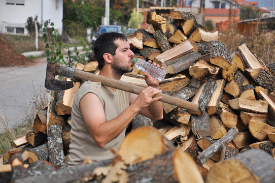 Tired lumberjack get rest and drink water. Lumberjack drink cold water to refresh after hard work - Powered by Adobe