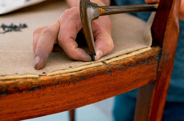a upholsterer repairs an antique chair