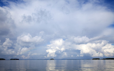 Naklejka na ściany i meble Cloudy sky reflecting on the calm sea