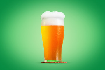 Glass of beer close-up with froth over green background