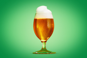 Glass of beer close-up with froth over green background