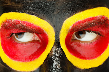 German sports fan patriot. Painted country flag on angry man face. Devil Eyes close up
