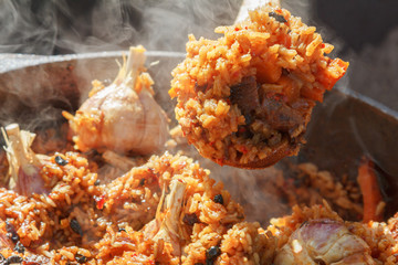 Preparation of pilaf on fire. Tourist bowler with food on bonfire, cooking in the hike, outdoor.