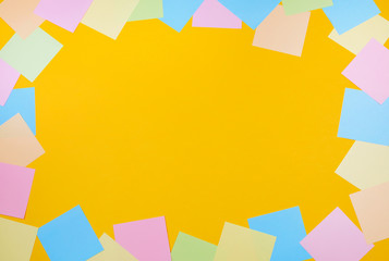 Blank colored note papers on a yellow background. Top view, copyspace.
