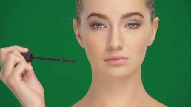 Girl applies mascara on the eyelashes with a makeup brush