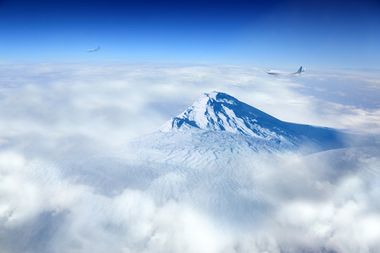 Fototapeta Samoloty pasażerskie i szczyt góry nad chmurami.