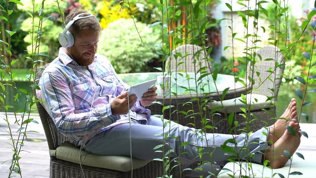 Man laughing while watching something funny on tablet in the garden
