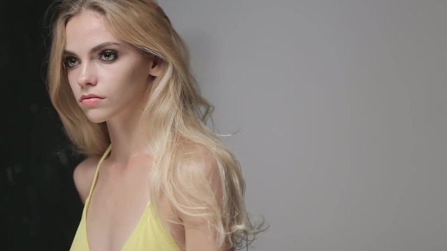 Sexual Caucasian model in a yellow bikini poses for a fashion photographer