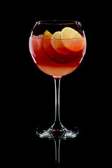 Cold sangria in a wine glass with reflection on black background