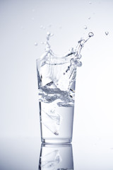 Ice cube falling into glass of water