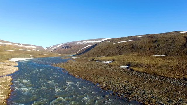 Beautiful aerial shot over a small river flowing through the arctic mountains ALTERNATIVE