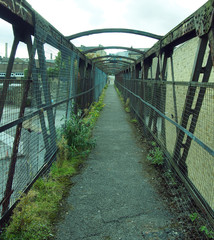 Fototapeta premium perspective view of an old rusting railway footbridge in halifax west yorkshire