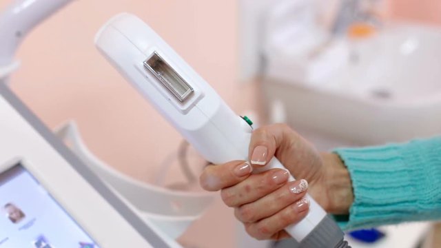 The girl on the display of a cosmetology unit has different modes of a cosmetology laser apparatus
