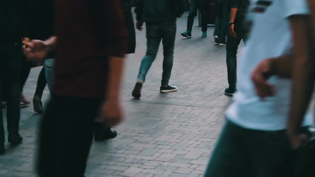 Crowd of passers-by goes along the street avenue. View of human feet in shoes