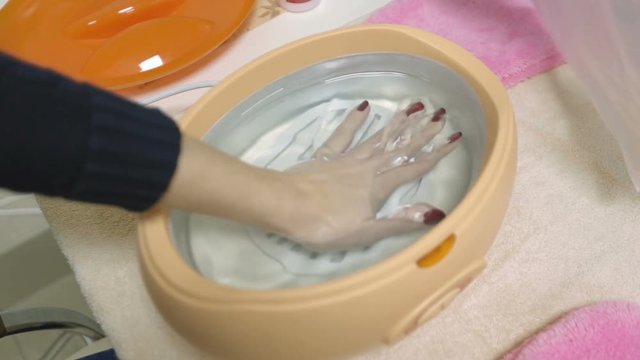 The girl dips her left hand into paraffin