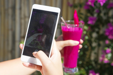 Female taking photo of fresh berry smoothie