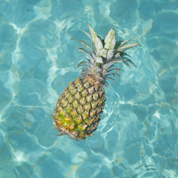 Pineapple floating in water - summer holidays, vacation and food concept
